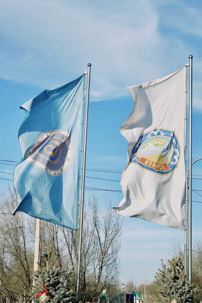 Flags of Konaev waving against a clear blue sky in Almaty Region, Kazakhstan.