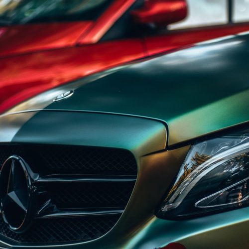 Detailed view of a luxury Mercedes Benz with focus on the emblem and headlight.