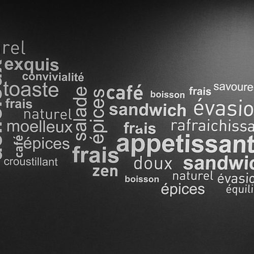 Monochrome word art on a cafe wall featuring French culinary terms.