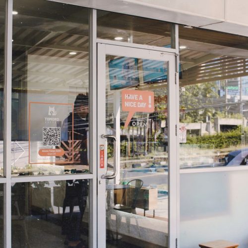 Glass door entrance to a cafe with signage reading 'Have a Nice Day'.