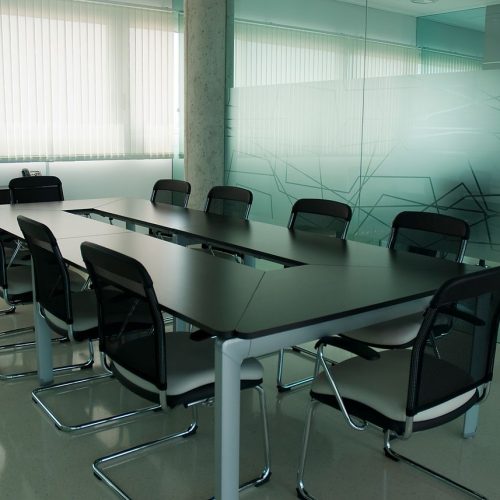 Elegant conference room with sleek black chairs and a modern glass wall design.