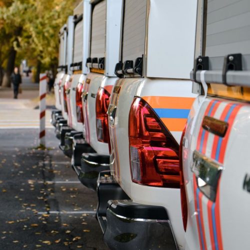 A row of pick-up trucks parked outdoors during autumn with falling leaves.